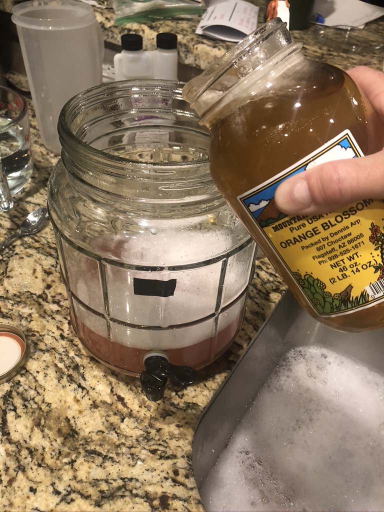 Adding honey to fermentor (water is pink due to rhubarb in this case)